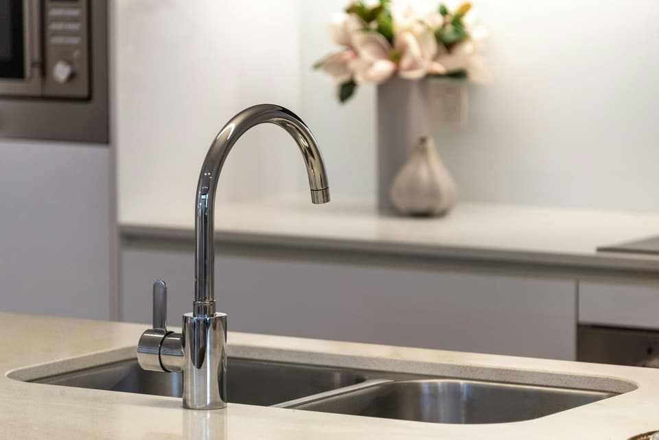 A chrome gooseneck faucet over a stainless steel double kitchen sink
